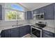Modern kitchen featuring navy cabinets, granite countertops, stainless steel appliances, and stylish tile backsplash at 19663 E Mann Creek Dr # D, Parker, CO 80134