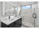 Bathroom featuring dual sinks, lighted mirror, and glass-enclosed shower at 1256 Yates St, Denver, CO 80204