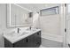 Modern bathroom featuring double vanity, tub with shower, and tile wall at 1256 Yates St, Denver, CO 80204