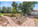 Picturesque backyard garden with stone pathways, flower beds, and a charming sitting area with mature trees at 7750 W 5Th Ave, Lakewood, CO 80226