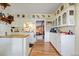 Functional kitchen with white cabinets, a brick accent, and wood floors, offering a cozy cooking space at 7750 W 5Th Ave, Lakewood, CO 80226