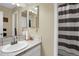 Cozy bathroom featuring a sink, mirror, vanity lighting, and a bathtub with a shower curtain at 3241 S Krameria St, Denver, CO 80222
