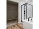 Modern bathroom featuring a walk-in closet, walk-in shower with black trim, a luxurious soaking tub and wood plank floors at 9474 Yampa St, Commerce City, CO 80022