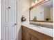 Bathroom vanity with wooden cabinets, granite countertop, large mirror, and white paneled door at 3724 S Poplar St, Denver, CO 80237
