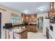Practical kitchen layout with granite countertops, wooden cabinetry, stainless sink, and a pass-through to a sunny dining area at 3724 S Poplar St, Denver, CO 80237