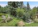 Lush backyard featuring a charming creek, bridge, Adirondack chairs and lovely landscaping at 1774 Upper Bear Creek Rd, Evergreen, CO 80439