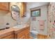 Cozy bathroom with wood cabinets, decorative mirror, and bright floral shower curtain at 1774 Upper Bear Creek Rd, Evergreen, CO 80439