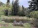 Picturesque pond surrounded by trees, with a wooden bench for relaxing at 1774 Upper Bear Creek Rd, Evergreen, CO 80439