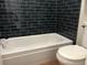 The tiled tub and shower in the bathroom is designed with black tiling and bright white grout at 5875 E Iliff Ave # 203, Denver, CO 80222