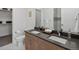 Bathroom with dual sink vanity, contemporary fixtures, walk-in closet, and tiled shower at 1898 S Bannock St # 209, Denver, CO 80223