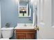 Stylish bathroom featuring a wood vanity, white sink, decorative mirror, and a charming blue painted wall at 3300 W Florida Ave # 117, Denver, CO 80219