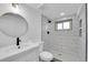 Modern bathroom with white tile shower, new fixtures, and circle framed mirror at 4642 Everett Ct, Wheat Ridge, CO 80033