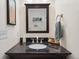 Bathroom vanity with a black counter, dark cabinets, and a framed mirror at 2681 Leyden St, Denver, CO 80207