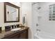 Bright bathroom with a dark vanity and a white tiled shower and glass block window at 2681 Leyden St, Denver, CO 80207