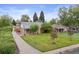 A cozy home has a manicured lawn and mature trees at 2681 Leyden St, Denver, CO 80207