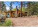 Charming exterior view of the home with a stone chimney, rustic wood siding, and a cozy mountain setting at 30930 Bear Cub Trl, Conifer, CO 80433