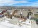 Aerial view of houses, and a street lined with parked cars, all with the snow-capped mountains in the background at 160 Pipit Lake Way, Erie, CO 80516