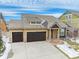 Aerial view of a charming home featuring a two-car garage, stone accents, and a welcoming front porch at 160 Pipit Lake Way, Erie, CO 80516