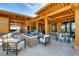 Inviting outdoor lounge area with a stone fireplace, cushioned seating, and timber pergola at 160 Pipit Lake Way, Erie, CO 80516