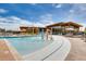 Community pool area with a splash pad, lounge chairs, and a modern clubhouse in the background at 160 Pipit Lake Way, Erie, CO 80516