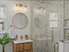 Bright bathroom featuring glass enclosed shower, floating wood vanity, gold hardware and a round mirror at 1640 E Virginia Ave, Denver, CO 80209