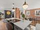 Modern kitchen island with a cooktop, views into the living and dining areas, exposed brick and stainless appliances at 1640 E Virginia Ave, Denver, CO 80209