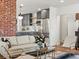 Cozy living room featuring an open layout, stylish decor, exposed brick column, and access to the modern kitchen at 1640 E Virginia Ave, Denver, CO 80209