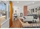 Bright open-concept living room showcasing hardwood floors, exposed brick and seamless flow to dining and kitchen at 1640 E Virginia Ave, Denver, CO 80209