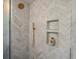 Stylish shower featuring white herringbone tile, gold shower head and fixtures, and built in shelving at 1640 E Virginia Ave, Denver, CO 80209