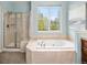 Bright bathroom features a shower and soaking tub with tile surround and a window with a green view at 19379 W 57Th Pl, Golden, CO 80403