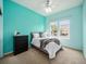 Bright bedroom with turquoise walls, a comfortable bed, and a black dresser, with views from two windows at 19379 W 57Th Pl, Golden, CO 80403