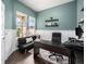 Stylish home office featuring a black desk, futon couch, a large window and dark wood floors at 19379 W 57Th Pl, Golden, CO 80403