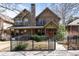 Inviting two-story home featuring a stone chimney, detailed trim, and a black fence at 2042 S Clayton St, Denver, CO 80210