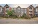 Condo's exterior with grey siding, brick accents, and landscaped grounds offers curb appeal at 14221 E 1St Dr # 303, Aurora, CO 80011