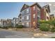 Exterior view of multi-story condo featuring gray siding, brick accents, and well-maintained landscaping at 14221 E 1St Dr # 303, Aurora, CO 80011