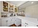 Bright home bar features white cabinetry, a countertop, and open shelving for storage and decor at 20855 Park Hollow Dr, Parker, CO 80138