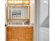 Bathroom with wooden vanity, granite countertop, decorative mirror, and stacked washer/dryer unit at 724 County Road 37, Brighton, CO 80603