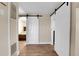 Hallway with barn door and views to a bedroom, with wood-style flooring at 724 County Road 37, Brighton, CO 80603