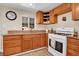 Well-lit kitchen featuring wooden cabinets, granite counters, and a white gas range at 724 County Road 37, Brighton, CO 80603
