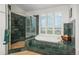 Bathroom featuring a glass shower, soaking tub with shutters and views, and green tile at 171 October Pl, Castle Rock, CO 80104