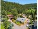 Aerial view of a charming yellow home featuring a deck, driveway with cars, and forestry in background at 4805 S Blue Spruce Rd, Evergreen, CO 80439