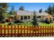 Charming yellow home with a gray roof, manicured lawn, and a decorative wooden fence at 4805 S Blue Spruce Rd, Evergreen, CO 80439