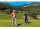 Golf course with two players and rolling hills in the background at 4805 S Blue Spruce Rd, Evergreen, CO 80439