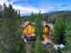 Aerial view of the wooded estate featuring a deck, hot tub, stone patio, and many large windows at 805 Highfield Trl, Breckenridge, CO 80424