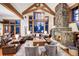 Cozy living room with stone fireplace, exposed beams, vaulted ceilings, and mountain view picture windows at 805 Highfield Trl, Breckenridge, CO 80424