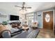 Inviting living room features a ceiling fan, front entry door, and cozy seating around a television and fireplace at 7960 Estes Ct, Arvada, CO 80005