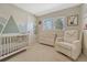 Cozy Bedroom featuring a crib, dresser, and comfortable rocking chair with ample natural light at 3680 S Glencoe St, Denver, CO 80237