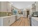 Updated kitchen with white cabinets, stainless steel appliances, herringbone backsplash, and hardwood floors at 3680 S Glencoe St, Denver, CO 80237