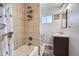 Clean bathroom featuring tiled shower over tub, vanity, and decorative mirror and artwork at 7217 Huron St, Denver, CO 80221