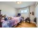 Bedroom with hardwood floors, a window with sheer curtains and a bed with a colorful comforter at 7217 Huron St, Denver, CO 80221